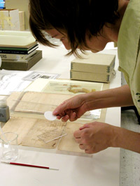 A conservator makes a repair to a document.