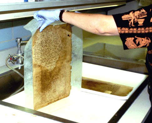 A conservator holding a manuscript page.