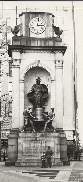 Side-by-side black and white photographs. Left image shows a crowd in coats and hats looking up at the statues of two men striking a bell with hammers.. The right image shows the same statues but only a man and a boy watching.
