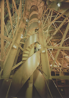 People stand on a spiral staircase surrounded by support beams inside the Statue of Liberty.