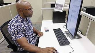 Cowboy wrangling bull with white horse running alongside.