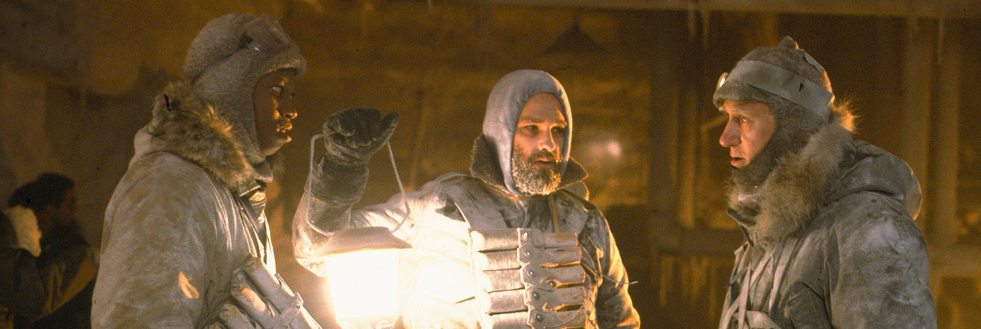 Three people dressed for cold, with one holding a lantern