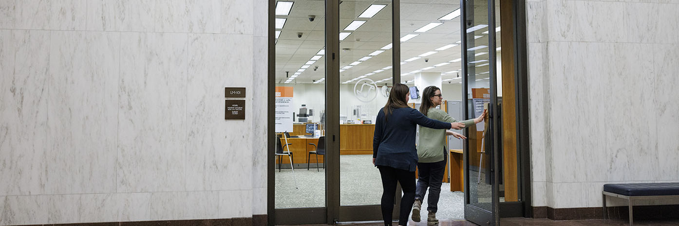 Two researchers open door and enter the Manuscript Reading Room.
