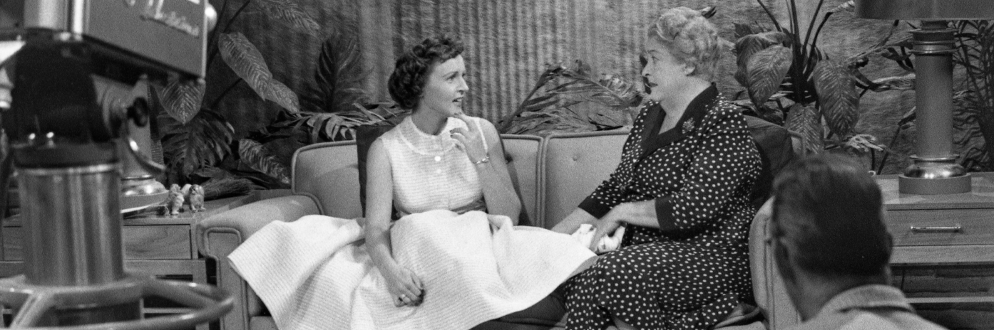 B&W image of Betty white and guest on the set of the Betty White Show. NBC camera and crew member visible